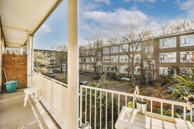 Beyaz balkondan park yeri ve ağaçları olan eski tuğla binaların panoramik manzarası