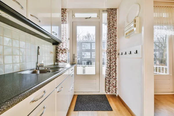 Interior of bright kitchen with balcony doors in modern apartment at daytime