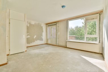 Evdeki boş ışık odasında, beyaz duvardaki plastik pencere ve radyatör.