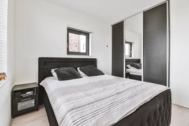 Pencerenin yanındaki konforlu yatak odası, güncel dairenin aydınlık yatak odası.