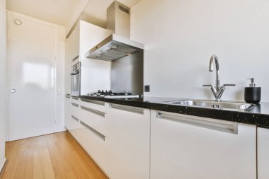 Modern ev mutfağı iç tasarımı beyaz dolaplar, dolaplar ve çelik kapüşon ile çağdaş apartman dairesinde.