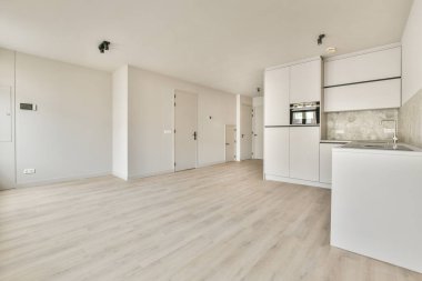 Penceresi olan boş, aydınlık bir oda ve şık bir mutfak köşesi.