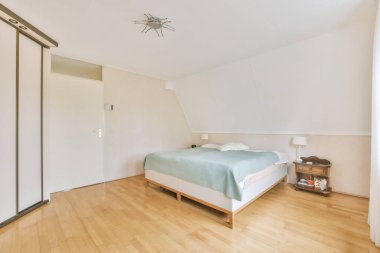 Modern minimalist tarzda pencereli mansard yatak odasındaki yeşil duvarın yanına konforlu yatak