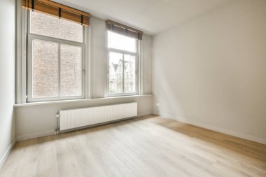 Evdeki boş ışık odasında, beyaz duvardaki plastik pencere ve radyatör.