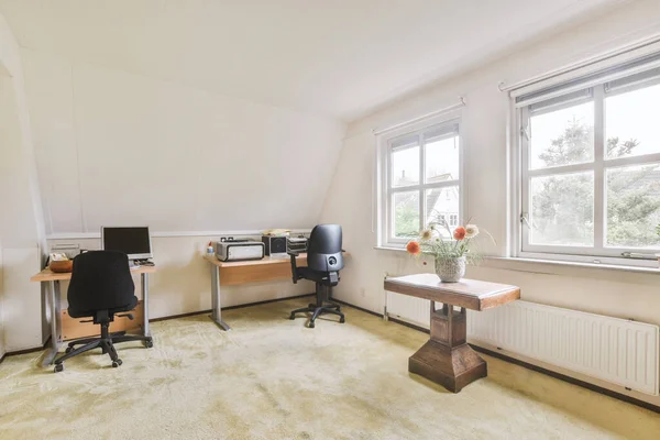 Minimalist interior of study room with parquet floor and white walls furnished with settee and table with shelf rack