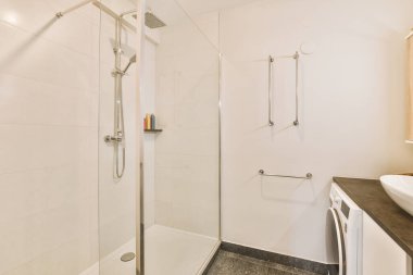 Küvetli modern banyo ve açık fayanslı ve beyaz tavanlı cam duş kabini.