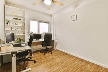 Modern ev ofisinin içi bilgisayar monitörleri ve beyaz pano ile modern apartmandaki hafif iş yerinde masanın yanına kurulmuş rahat sandalye.