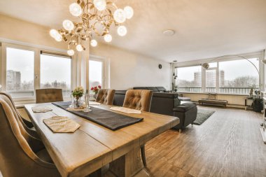 Masanın etrafına, modern dairede şık oturma odasının yemek alanında dekorasyonlar yerleştirilmiş kanepe ve koltuklar.