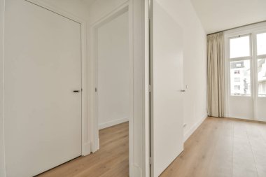 Giriş kapısı, beyaz duvarları ve parke zemini lambayla aydınlatılmış, geometrik tasarımı olan boş, modern bir daire.