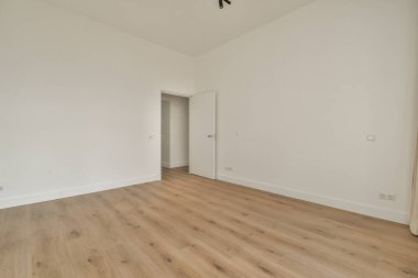 Giriş kapısı, beyaz duvarları ve parke zemini lambayla aydınlatılmış, geometrik tasarımı olan boş, modern bir daire.