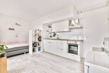 Çağdaş dairenin geniş odasındaki dinlenme odası ve mutfağın yakınındaki sandalyeli ve çiçekli masa.