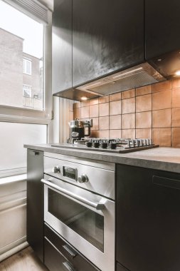 Minimalist tarzı siyah mobilyalı, lavabolu ve sobalı bir ev mutfağı.