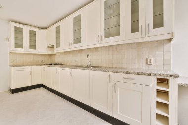 Pencereleri ve ahşap parke zemini olan boş beyaz mutfağın içi.