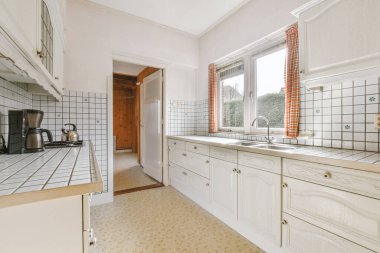 Çağdaş mutfakta dolaplara ve fırına karşı egzoz kapağının altındaki tezgahların yanına yerleştirilmiş rahat sandalyeler.