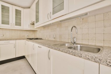 Pencereleri ve ahşap parke zemini olan boş beyaz mutfağın içi.