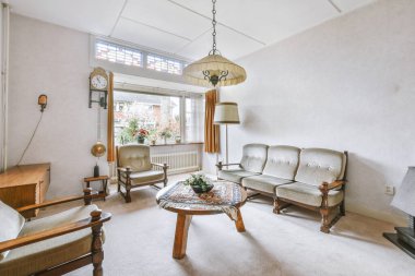 Sandalyeleri ve vazosu olan eski püskü ahşap masa modern apartmanda dekorasyonlu aydınlık duvarlara karşı rahat kanepenin yanında.