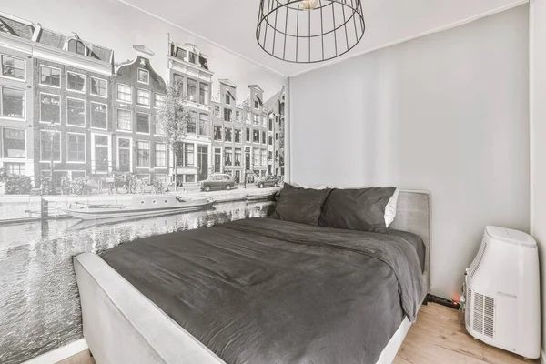 Minimalist interior design of small bedroom with soft bed placed in corner and wooden table with lamp illumination