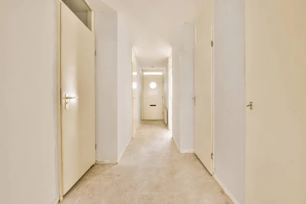 木の床の上に白い壁と輝くランプの多くのドアを持つ光の狭い廊下 — ストック写真