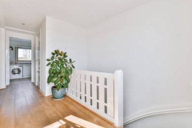 Çerçevelenmiş resimlerin yanındaki beyaz oda kapısı ve evdeki merdivenlerin üstündeki şık lamba.