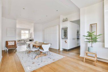 Modern apartmandaki geniş minimalist tarzda oturma odasında halı ve masaya yakın rahat bir kanepe.