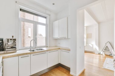 Minimalist tarzı beyaz mobilyalı, lavabolu ve sobalı bir ev mutfağı.