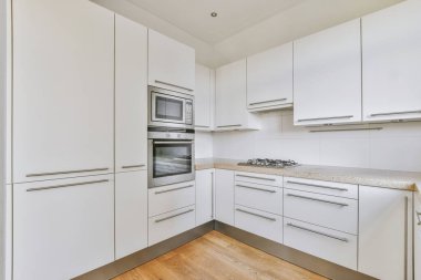 Minimalist tarzı beyaz mobilyalı, lavabolu ve sobalı bir ev mutfağı.