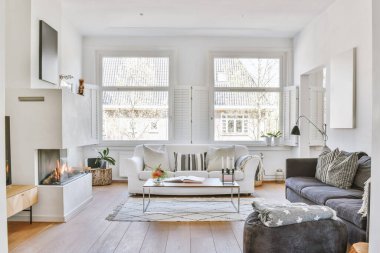 Modern apartmandaki geniş minimalist tarzda oturma odasında halı ve masaya yakın rahat bir kanepe.