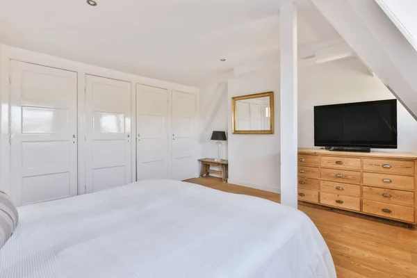 Interior of contemporary bedroom with white walls and open bathroom in attic of house