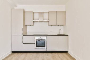 Soba ve fırın kapüşonlu boş beyaz mutfak ve ahşap parke zemin.