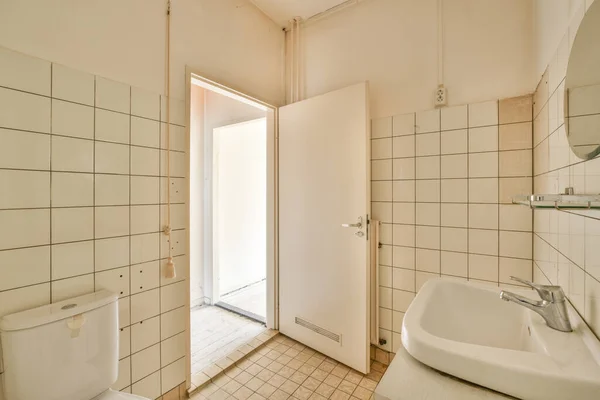 Interior of contemporary bathroom with shabby beige walls and partitions and white door at home