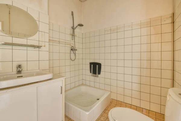 Interior of contemporary bathroom with shabby beige walls and partitions and white door at home