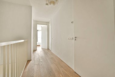 Çerçevelenmiş resimlerin yanındaki beyaz oda kapısı ve evdeki merdivenlerin üstündeki şık lamba.