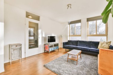 Yastıkları olan rahat bir kanepe. Duvara yaslanmış TV ve dekorasyonlar modern sevgi odasında.