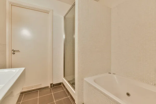 Interior of contemporary bathroom with shabby beige walls and partitions and white door at home