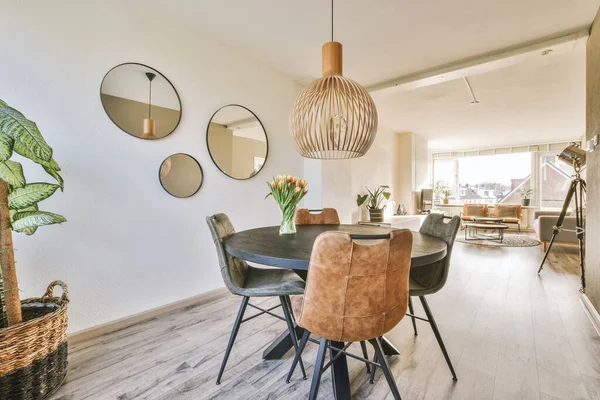 Simple interior of light living room with gray sofa in front of TV and dining table against window