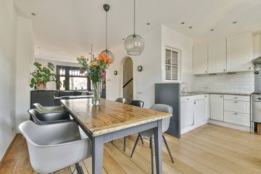 Modern oturma odasında cam kolyenin altında çiçek vazosu olan ahşap masa.