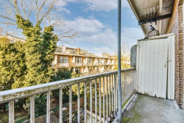 Eski tuğla binaların panoramik manzarası. Küçük balkondan park yerleri ve ağaçlar.