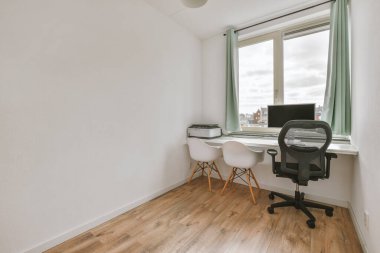 Çalışma odasının minimalist içinde parke zemin ve masa ve kanepe döşeli beyaz duvarlar.