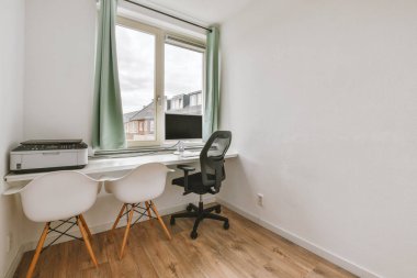 Çalışma odasının minimalist içinde parke zemin ve masa ve kanepe döşeli beyaz duvarlar.