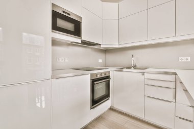 Pencereleri ve ahşap parke zemini olan boş beyaz mutfağın içi.