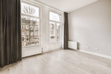 Pencereleri ve ahşap parke zemini olan boş beyaz mutfağın içi.