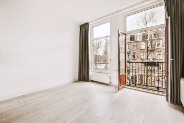 Pencereleri ve ahşap parke zemini olan boş beyaz mutfağın içi.