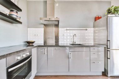 Modern ev mutfağı iç tasarımı beyaz dolaplar, dolaplar ve çelik kapüşon ile çağdaş apartmanda.