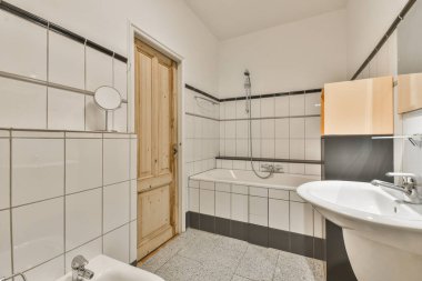 Aynalı lavabolar ve modern banyoda beyaz fayanslı duvarları olan temiz bir küvet.