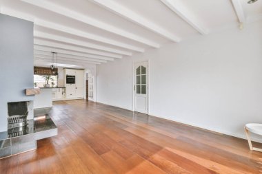 Şömineli boş oda ve beyaz ışıklı tavanlı mutfak alanı.