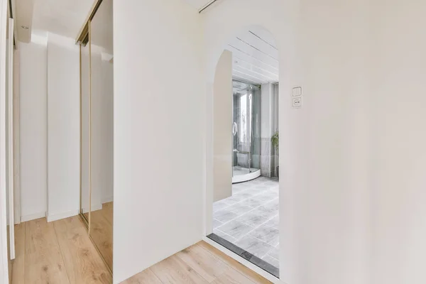 白い壁とバスルームへのアーチ型の入り口と寄木細工の床の回廊 — ストック写真