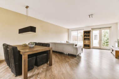 Balkon kapısının yanında yastıklar ve puf bulunan rahat bir kanepe ve çağdaş bir dairenin yemek odası.