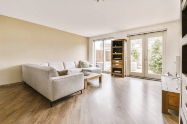 Balkon kapısının yanında yastıklar ve puf bulunan rahat bir kanepe ve çağdaş bir dairenin yemek odası.