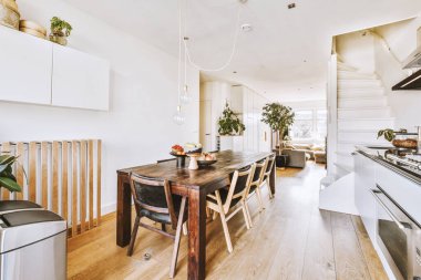 Pandantif lambanın altındaki ahşap yemek masası açık mutfak ve oturma odası.