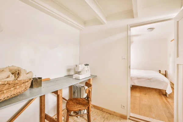 ベッドルームの横にある白い梁天井の明るい部屋にミシン バスケット ラジエーター付きのテーブル — ストック写真